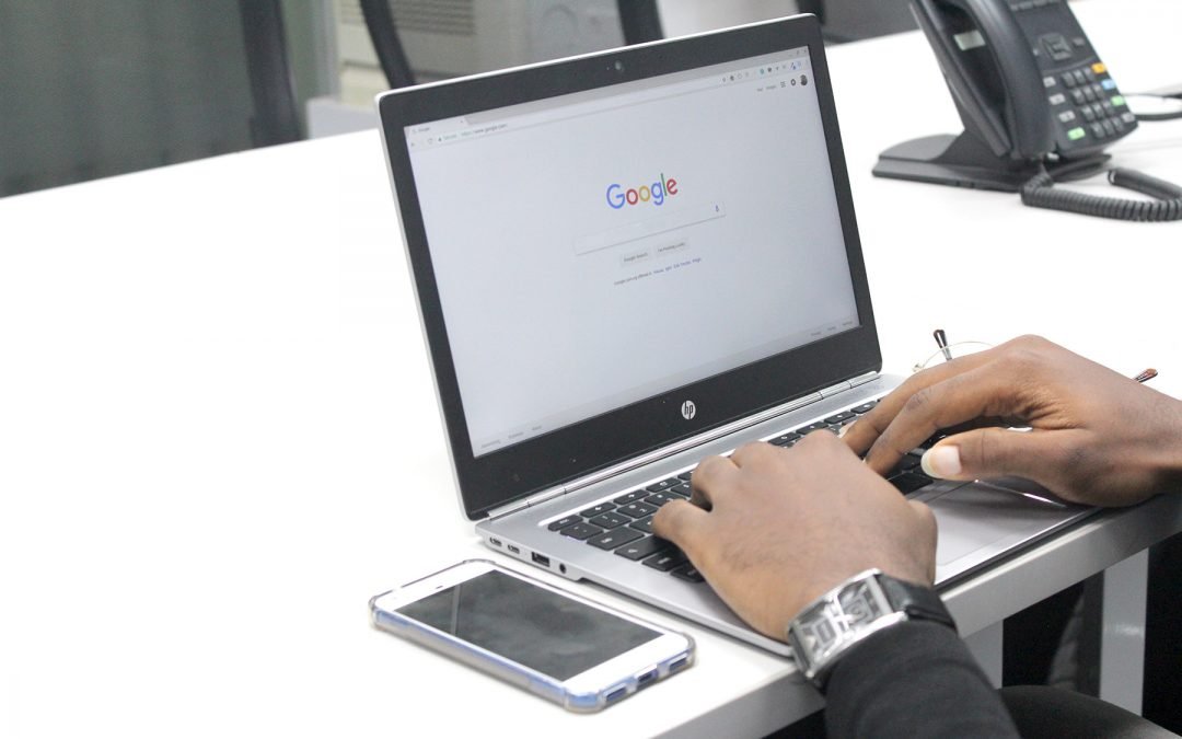 A person types onto a laptop to conduct a Google search.
