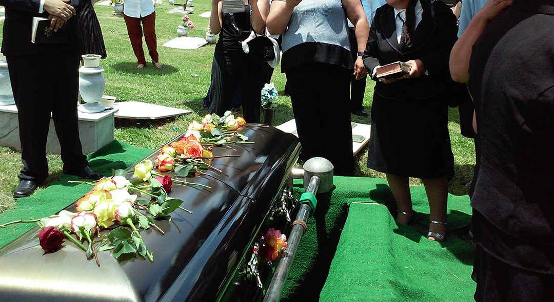 A black casket is covered with flowers at a fentanyl drug overdose funeral.